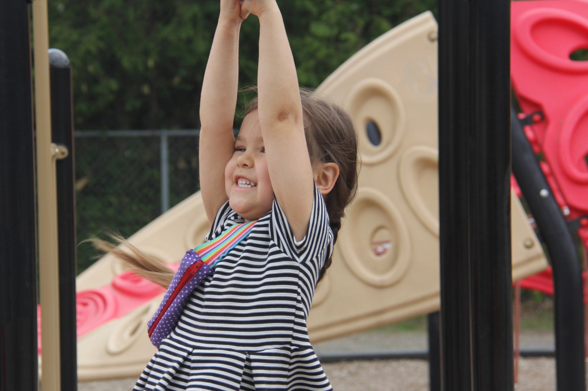 A child swinging on a play structure while wearing an epicute EpiPen / Allerject / Emerade case.
